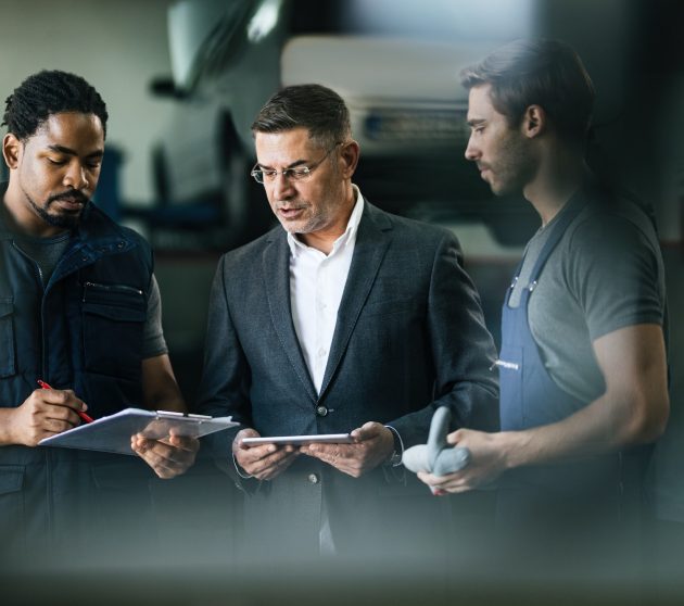 Auto mechanics and their manager analyzing reports in repair shop.
